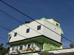 托卢Apartamento Tolu的白色绿色的建筑,设有蓝色的窗户