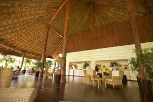 艾库玛尔Akumal Bay Beach & Wellness Resort的餐厅设有大型稻草屋顶和桌椅