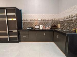 珍南海滩Ku's Roomstay的厨房配有黑色橱柜和瓷砖墙。