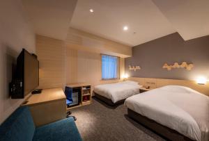 高知JR Clement Inn Kochi的酒店客房设有两张床和一台平面电视。