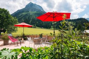 莱赫阿尔贝格布劳纳尔公寓的一个带椅子和红色遮阳伞的庭院和山