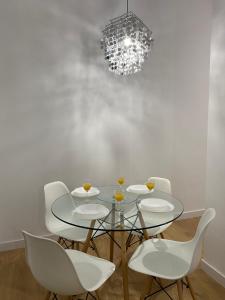 马德里Aluche Aparment B的一间设有玻璃桌和白色椅子的用餐室