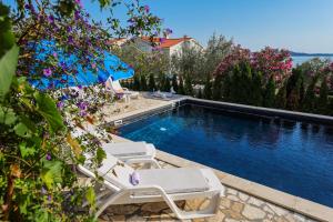 科济诺Luton Apartment Zadar Kozino Heating Pool & Jacuzzi的一个带2把躺椅和鲜花的游泳池