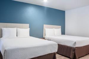 阿马里洛WoodSpring Suites Amarillo East I-40的蓝色墙壁客房的两张床