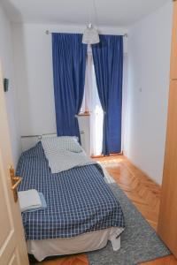 皮罗特Apartman Marija的一间卧室配有床和蓝色窗帘的窗户