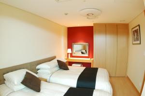西归浦市Keumho Jeju Resort的红色墙壁的酒店客房内的两张床