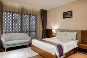 胡志明市DHTS Business Hotel & Apartment的卧室配有床、椅子和窗户。