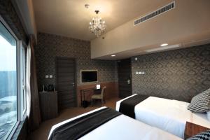 香港华美达华丽酒店的一间卧室配有两张床、一张书桌和一个吊灯。