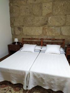 贡多马尔A casa de Carmiña的卧室配有白色的床铺和石墙
