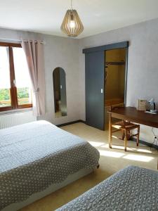 于讷河畔索镇Logis hôtel Les Confins du perche的一间卧室配有两张床、一张桌子和一架钢琴