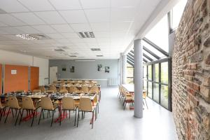 雷恩Auberge de Jeunesse HI Rennes的一个带桌椅的教室,位于带窗户的房间