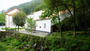 阿马里什Casa Abrigo do Lagar的森林旁的白色建筑,红色的大门