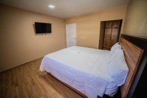 Los AlgodonesCalifornia Comfort & Suites的卧室配有白色的床和平面电视。