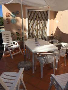 圣特雷莎加卢拉Casa Maltinu的客房内的白色桌椅和遮阳伞