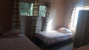 LephalaleAbuelita Guesthouse - Room 3的一间卧室设有两张床和两个窗户。