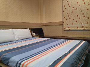 台南The LEY HOTEL 寶麗頌旅館的一张床上,床上有一条色彩缤纷的条纹毯子