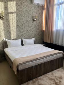 阿克套Tarlan Hotel的卧室内的一张带白色床单和枕头的床
