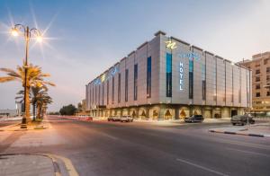 阿可贺巴Naviti Warwick Al Khobar的一条有道路的城市街道上的大型建筑