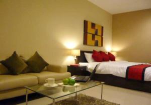 曼谷拉查达雅庭13公寓式酒店 的一间卧室配有一张床、一张沙发和一张桌子