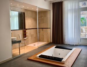 锡拉库扎Isabella di Castiglia Apartments的带浴缸和玻璃淋浴间的浴室。