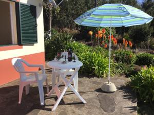 蓬塔杜帕戈Bungalows Do Amparo的一张桌子和两把椅子以及一把雨伞