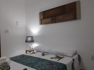 贝贝里比Villa Arte Pousada Morro Branco的一间卧室配有一张床和一张带台灯的桌子