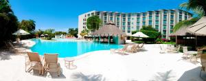 伊斯塔帕Gamma Plaza Ixtapa的一个带椅子的游泳池和一个位于酒店后面的酒店