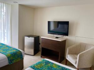 拉巴斯拉巴斯马雷贡七冠酒店的一间卧室配有电视、一张床和一把椅子