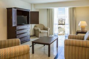 华雷斯城华雷斯城费斯塔酒店的客厅配有电视、椅子和桌子