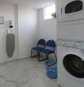 锡劳锡劳One酒店的洗衣房配有2把蓝色椅子和洗衣机