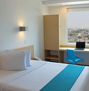 锡劳锡劳One酒店的一间卧室配有一张床、一张书桌和一个窗户。
