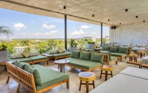 坎昆Mex Hoteles的一间设有绿色家具和大窗户的餐厅