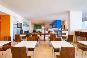 巴亚尔塔港巴亚尔塔港机场One酒店的空的饭厅,配有桌椅