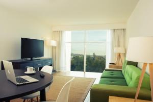 库利亚坎库利亚坎嘉年华酒店的客厅配有绿色沙发、书桌和笔记本电脑