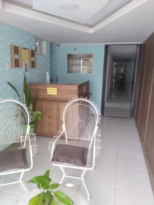 瓜拉派瑞Pousada Solar da Praia的一间设有两把白色椅子和柜台的等候室