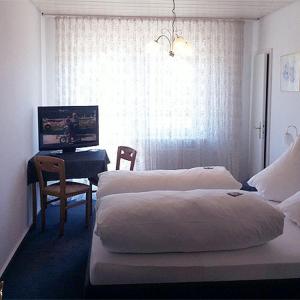 Kirchheim am Neckar乌尔曼斯霍夫旅馆的酒店客房设有两张床、一张桌子和一台电视。