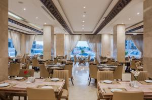 阿可贺巴Naviti Warwick Al Khobar的餐厅设有木桌、椅子和窗户。