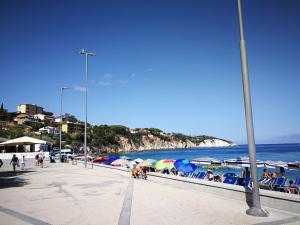 费拉约港Appartamenti Acquazzurra的坐在海滩上的人,有遮阳伞和海洋