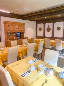 采尔马特阿多尼斯酒店的用餐室配有黄色桌子和白色椅子