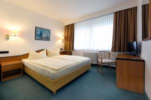 艾森许滕施塔特LAT Hotel & Apartmenthaus Berlin的配有一张床和一把椅子的酒店客房