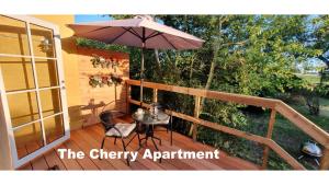 伦讷The Cherry Apartment - 'Den Gule Svane' Guest House near Rønne & Beach的庭院配有遮阳伞和桌椅。