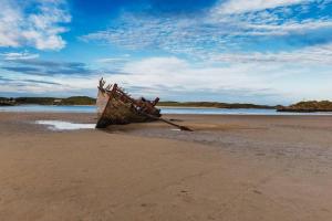 GweedoreLuí na Gréine的海滩上沙子上的一艘老船