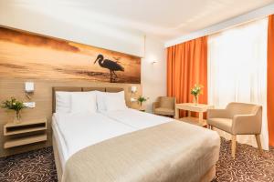 切霍齐内克Hotel Amazonka Conference and Spa的一间酒店客房,墙上有一张床和一只鸟
