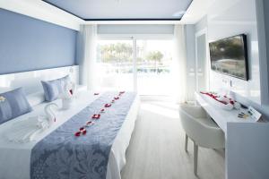 卡斯特尔德费尔斯马思德地中海Spa公寓式酒店的一间卧室,配有一张长桌子和红玫瑰