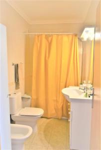 阿尔布费拉Ritta's house的浴室设有卫生间和黄色的淋浴帘