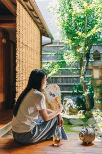 京都希促间旅馆的坐在地板上的女士,带风扇