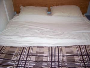Canora度假小屋酒店的一张带白色床单和枕头的未铺好的床