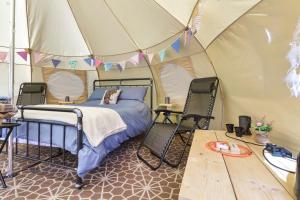 Little HautboisPitch Perfect Glamping Norfolk的帐篷内的一张床位,配有两把椅子和一张桌子