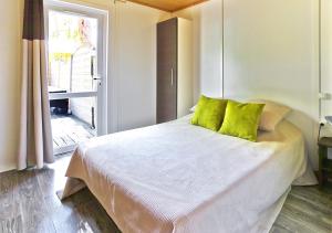 比居格利亚Camping San Damiano的一间卧室配有一张带绿色枕头的床和一扇窗户