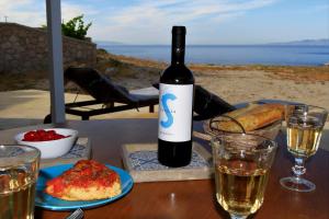 Mandrakia爱琴海蓝色度假屋的桌子上摆放着一瓶葡萄酒和眼镜